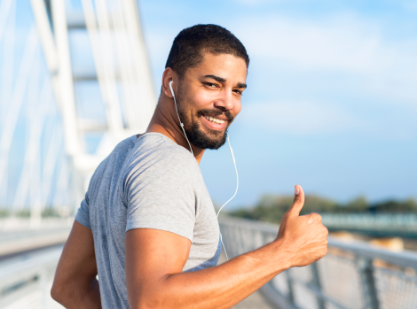 smiling-athlete-with-earphones-holding-thumbs-up-ready-training 1